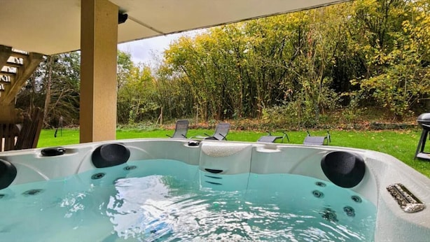 A hot tub with a built-in staircase, surrounded by a grassy area with lounge chairs and a barbecue grill. - Private 3-seater Jacuzzi, garden, air conditioning & parking - Dieulouard A31 (Dieulouard)