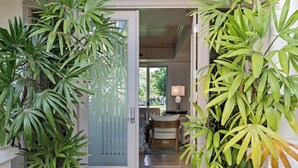 A doorway with a frosted glass door, a small table with a lamp, and a chair inside. - Recently Renovated | Impeccable Design | Pro Managed | Islands at Mauna Lani D2 (Kamuela)