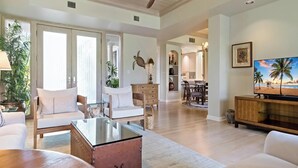 A spacious living room with a ceiling fan, a dining area, and a kitchen in the background. - Recently Renovated | Impeccable Design | Pro Managed | Islands at Mauna Lani D2 (Kamuela)