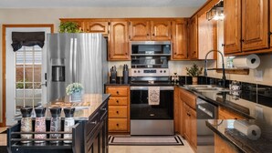 Une cuisine moderne avec des meubles en bois, des appareils électroménagers en acier inoxydable et un plan de travail noir.