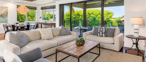 A spacious living area with a large sofa, a coffee table, and a dining table with chairs.
