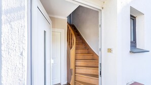 Una scala che porta a una porta, una piccola finestra e un muro bianco.