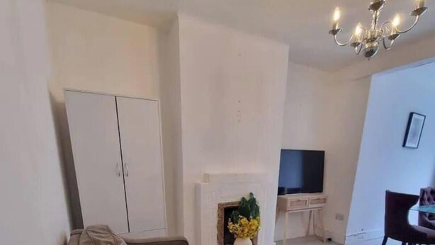 A living room with a sofa, a fireplace, a television, and a chandelier. - London Serenity House - 4 Bedrooms (London)