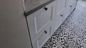 A kitchen with white cabinets, a white tiled backsplash, and a patterned floor. - London Serenity House - 4 Bedrooms (London)
