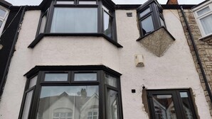 A corner house with a white exterior, black-framed windows, and a visible door. - London Serenity House - 4 Bedrooms (London)