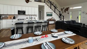 Une cuisine spacieuse avec des meubles blancs, une tête de cerf accrochée au mur et un coin repas aménagé pour quatre personnes, avec une table et des chaises en bois.
