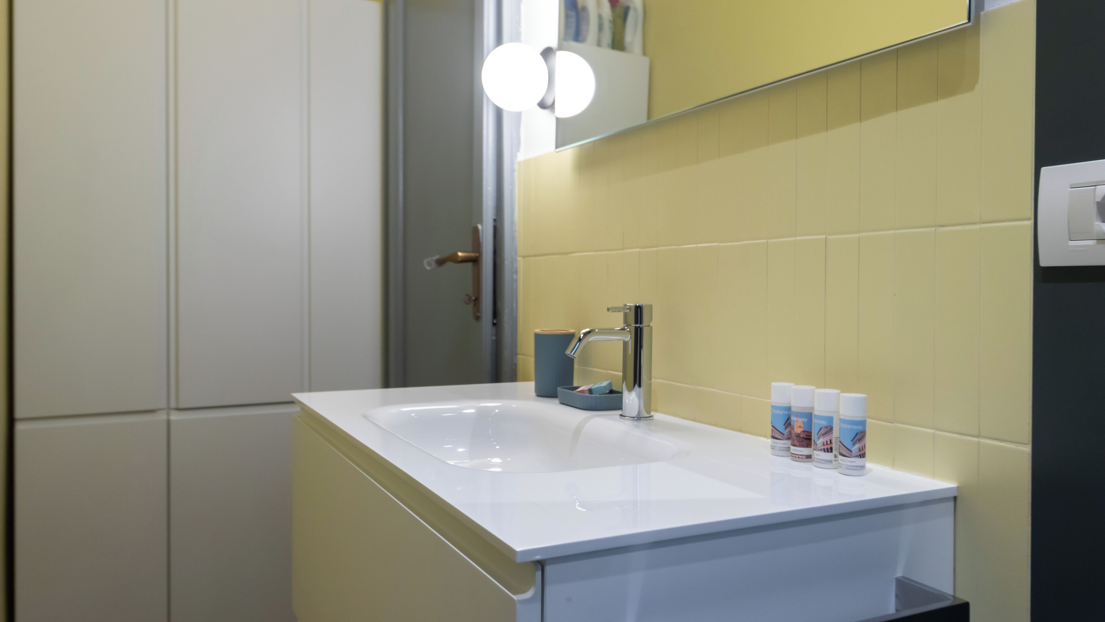 A bathroom with a white sink, a mirror, and toiletries.