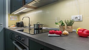 Una cucina moderna con elettrodomestici in acciaio inox, un lavandino e una selezione di frutta e verdura fresca sul bancone.