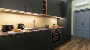 Una cucina moderna con mobili scuri, un lavello in acciaio inossidabile, forno integrato e pavimento in legno.