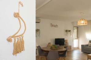 A modern living room with a dining area, a TV, and a wall-mounted macrame decoration. - 3-bedroom apartment in fabulous Benicàssim with AC/HEATER (Benicàssim)
