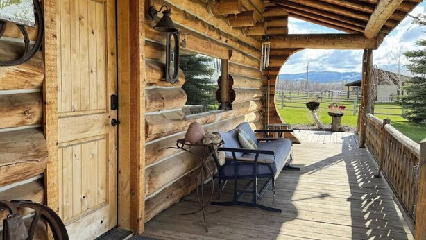 A log cabin with a wooden porch, a bench, and a table with chairs. - Susie’s Place - Cozy Cabin (Bozeman)