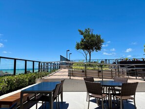A rooftop patio with outdoor seating, a tree, and a view of the ocean. - Move Tambau 108 (João Pessoa)