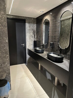 A modern bathroom with two sinks, a large mirror, and a door. - Move Tambau 108 (João Pessoa)
