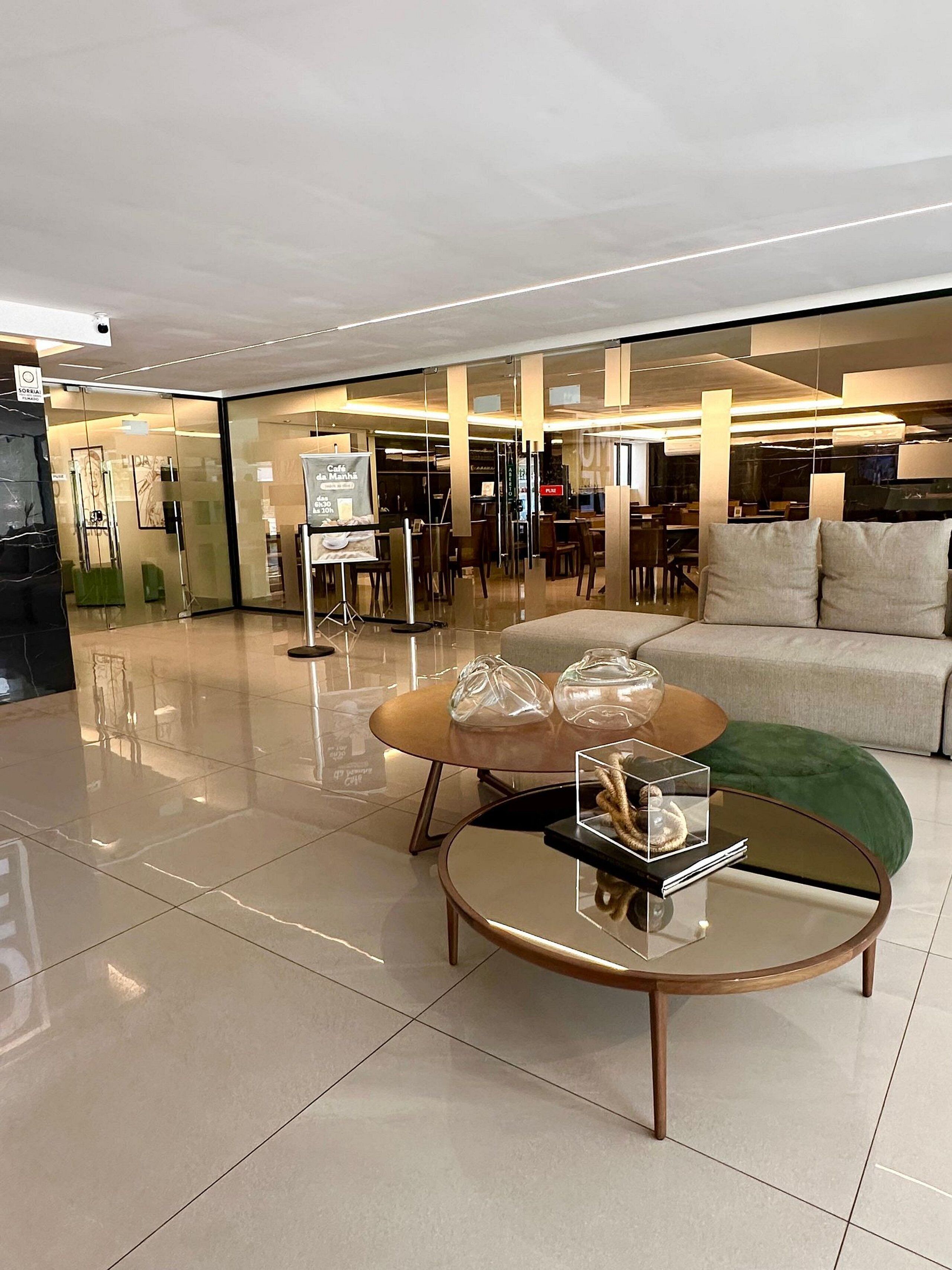 Un interior moderno con una mesa de centro de vidrio, un sofá y un comedor con sillas y mesas.
