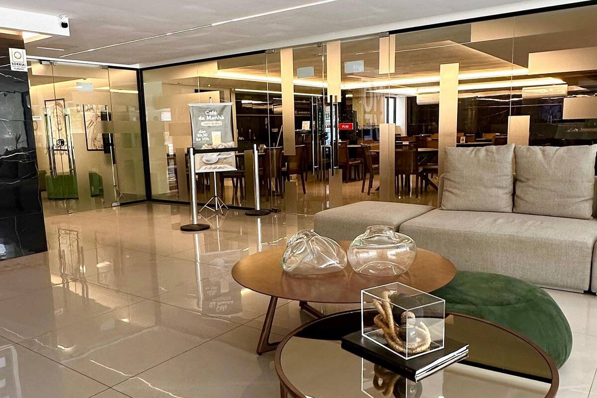 A modern interior with a glass coffee table, a sofa, and a dining area with chairs and tables.