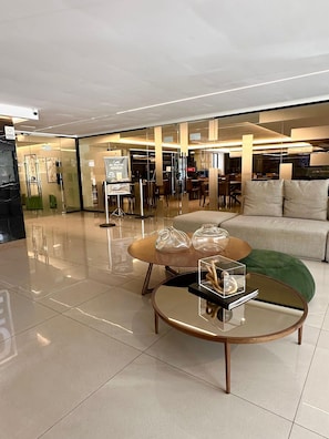 A modern interior with a glass coffee table, a sofa, and a dining area with chairs and tables.