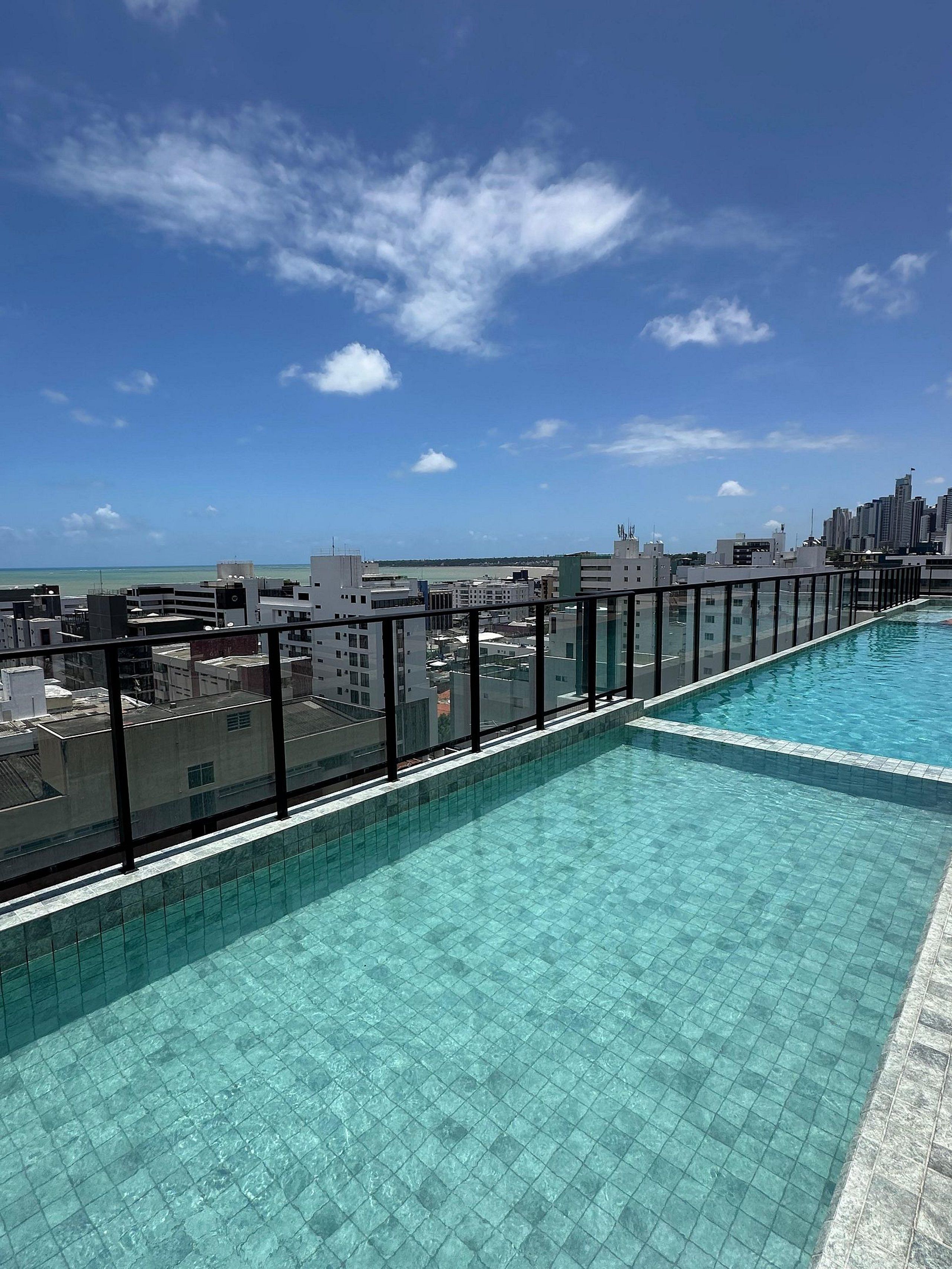 A rooftop swimming pool with a city view, surrounded by buildings.