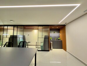 A modern conference room with a long table, chairs, a small kitchenette, and a sliding glass partition. - Move Tambau 108 (João Pessoa)