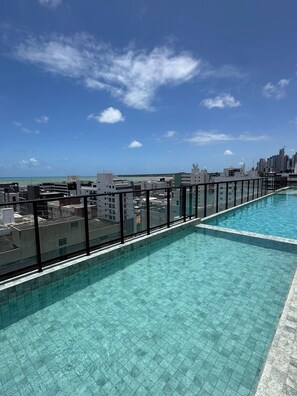 A rooftop swimming pool with a city view, surrounded by buildings.