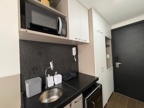 A compact kitchen with a built-in microwave, a stainless steel sink, and white cabinets.