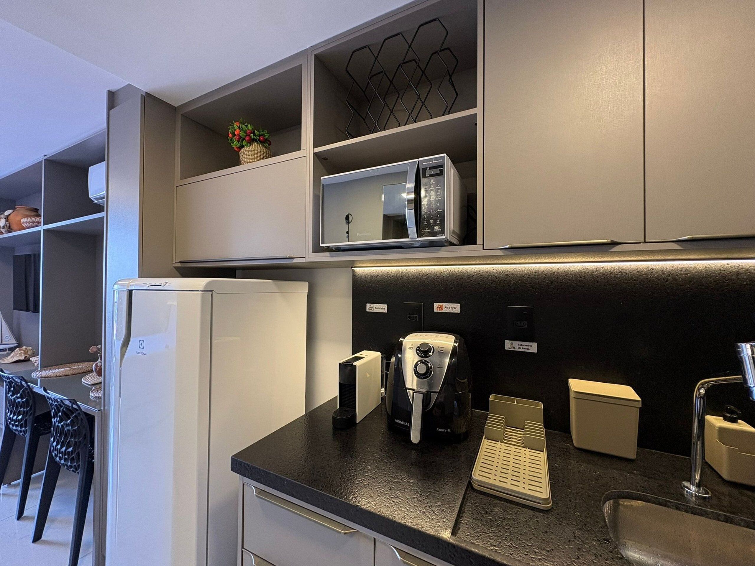 Una cocina moderna con microondas integrado, cafetera y hervidor sobre la encimera.