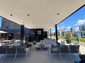 An outdoor seating area with modern furniture, a 'MOVE' sign, and a city view. - Move Tambau 108 (João Pessoa)