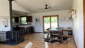 Un vaste espace de vie doté d’une cheminée, de parquet, d’une table à manger et d’une cuisine située à l’arrière-plan.