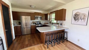 Une cuisine moderne dotée d’appareils électroménagers en acier inoxydable, de meubles en bois et d’un îlot central avec des tabourets.