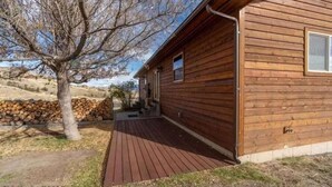 Une cabane en bois dotée d’une terrasse en bois, avec une pile de bois de chauffage au premier plan.