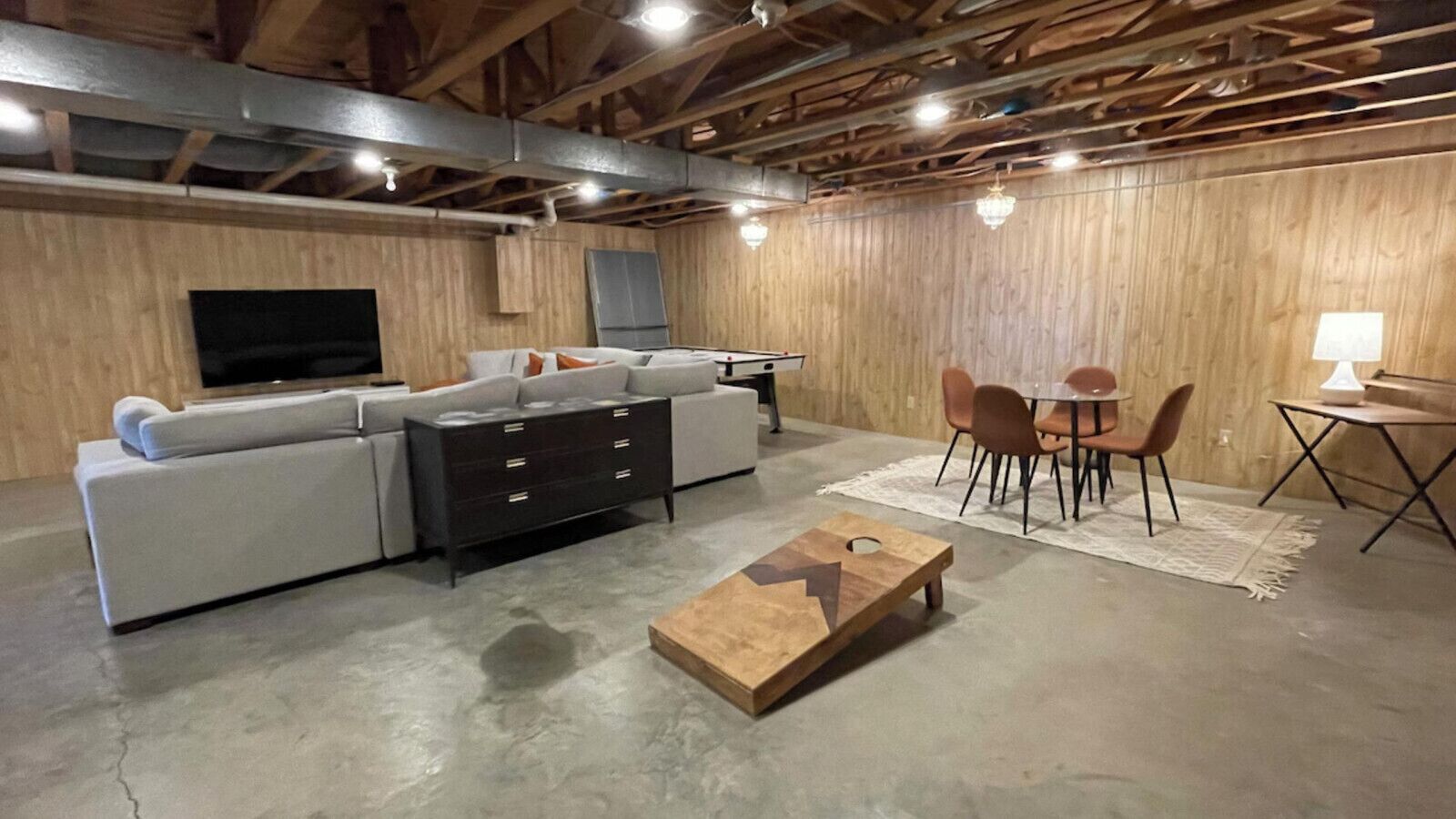 Een moderne woonkamer met een hoekbank, een houten salontafel en een eethoek met een tafel en stoelen.