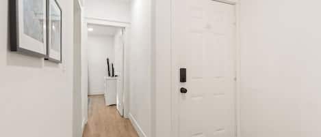 Ein Flur mit einer weißen Tür, Holzboden und einem gerahmten Bild an der Wand.