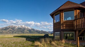Une cabane en bois dotée d’un balcon, située dans un cadre montagneux.