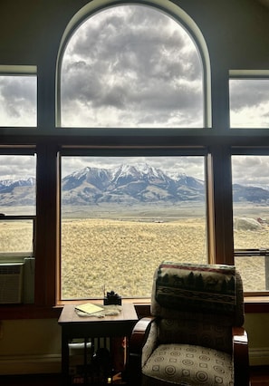A room with a large arched window overlooking a mountainous landscape.