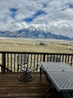 A deck with a table and chairs overlooking a mountainous landscape.