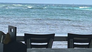 Vista desde un espacio cubierto con una mesa y sillas, sobre un mar agitado con olas y una boya a lo lejos.
