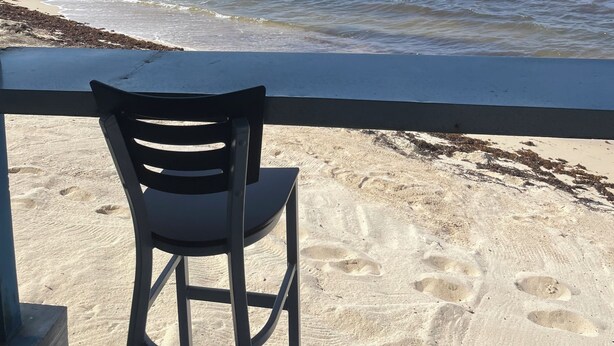 Vista a la playa desde un espacio cubierto con una silla.