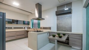 A modern kitchen with a central island, built-in appliances, and a large window. - Blue House (Rio de Janeiro)