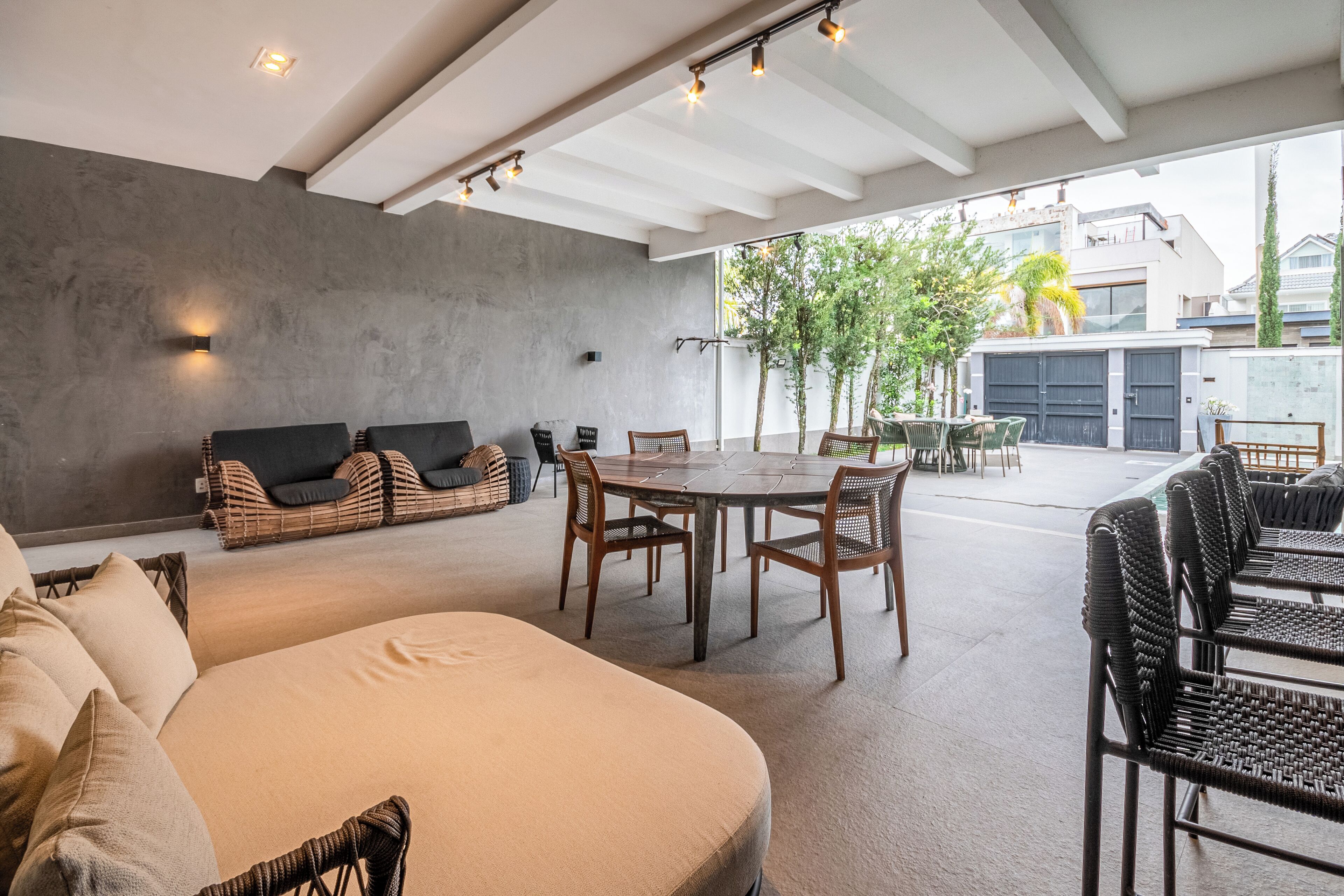 Un espacio habitable abierto con sofá, una mesa de comedor y sillas, una pared de concreto y vistas al exterior.