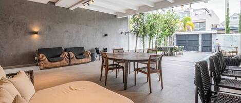 Un espacio habitable abierto con sofá, una mesa de comedor y sillas, una pared de concreto y vistas al exterior.