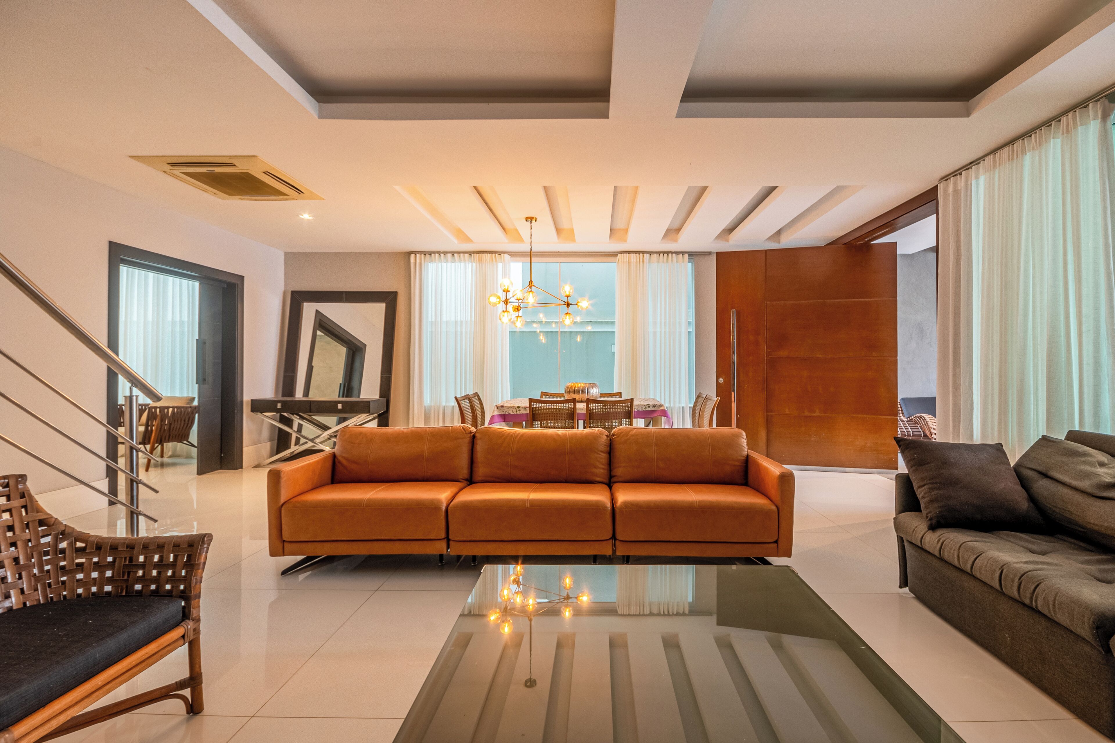 A modern living room with a sofa, a coffee table, and a dining area with a table and chairs.