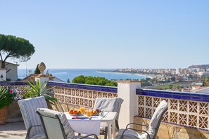 Eine Terrasse mit Frühstückstisch, mit Blick auf eine Küstenstadt.