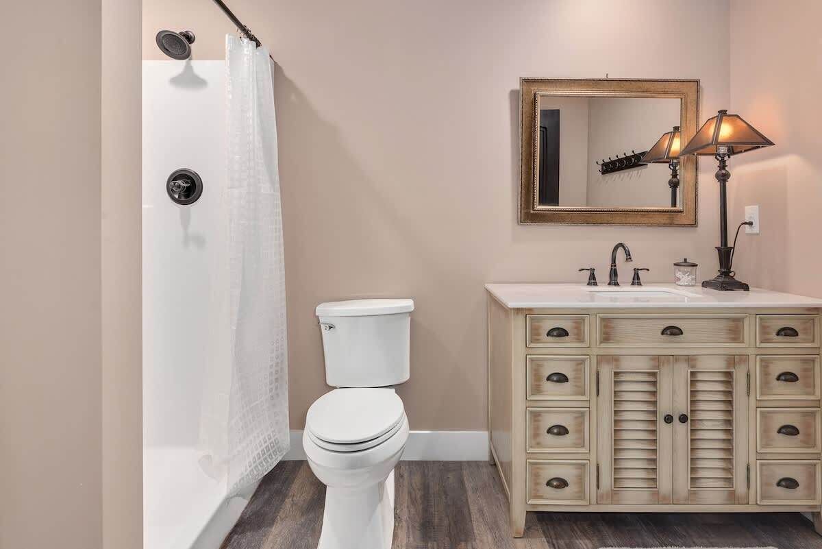 Un bagno con doccia, toilette, mobile lavabo con cassetti e specchio.