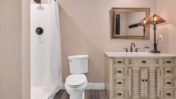 Un bagno con doccia, toilette, mobile lavabo con cassetti e specchio.