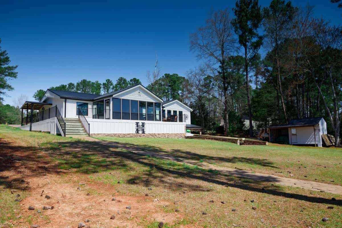 A two-story house with a large front porch, a covered patio, and a small attached garage.
