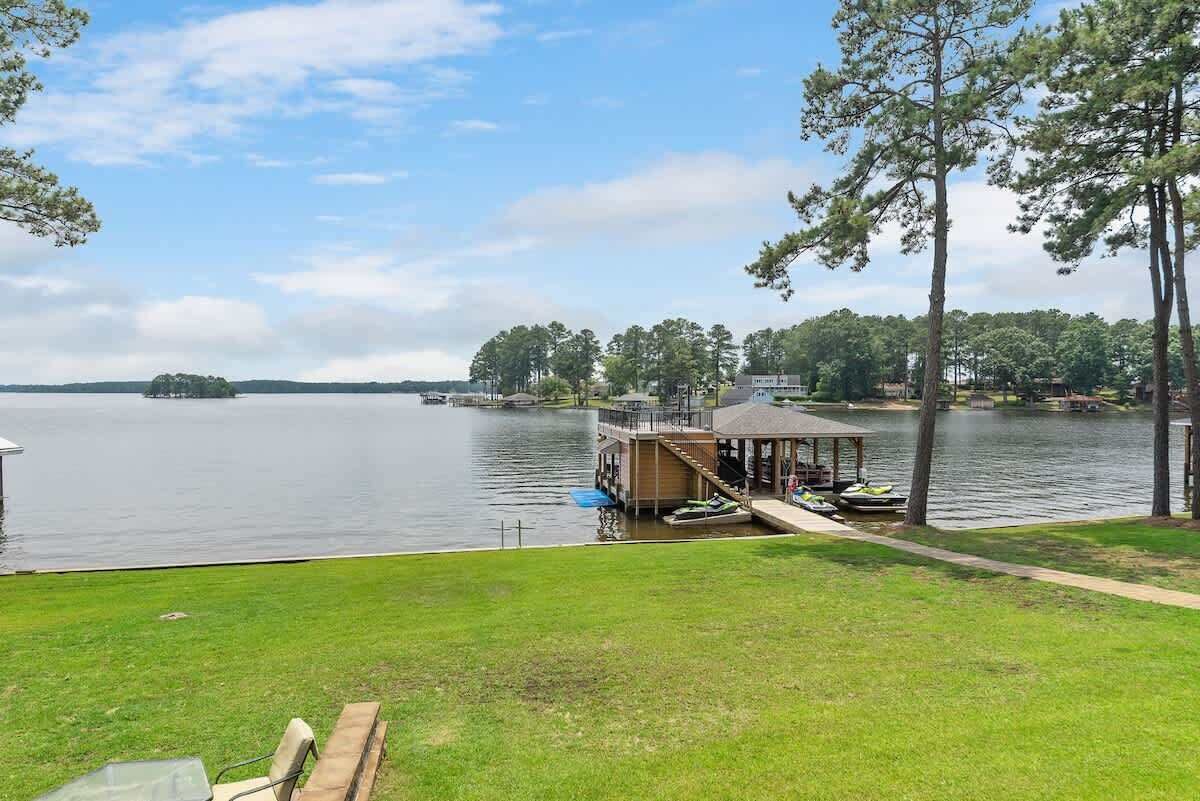 A lakeside property with a dock, a covered area, and a grassy lawn.