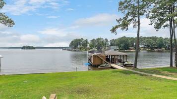A lakeside property with a dock, a covered area, and a grassy lawn.