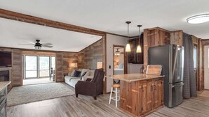 Un espacio habitable amplio con un ventanal grande, un ventilador de techo y piso de madera.