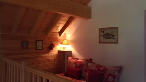 A wooden interior with a sloped ceiling, a lamp, a couch with patterned cushions, and a framed picture on the wall. - Chalet 'Limondin' with Mountain View, Private Terrace and Balcony (Mizoën)