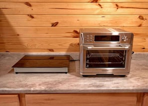 Una cocina con una encimera, horno tostador y pared de madera.