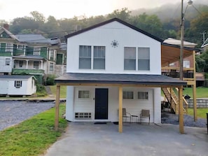 Ein zweistöckiges Haus mit überdachter Veranda, Garage und einer Treppe, die zu einer oberen Ebene führt.